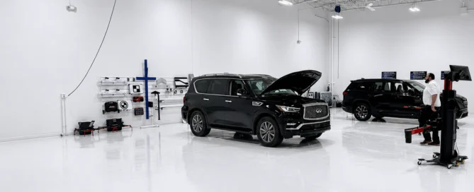 Multiple vehicles staged in a clean ADAS calibration bay with alignment equipment and technician